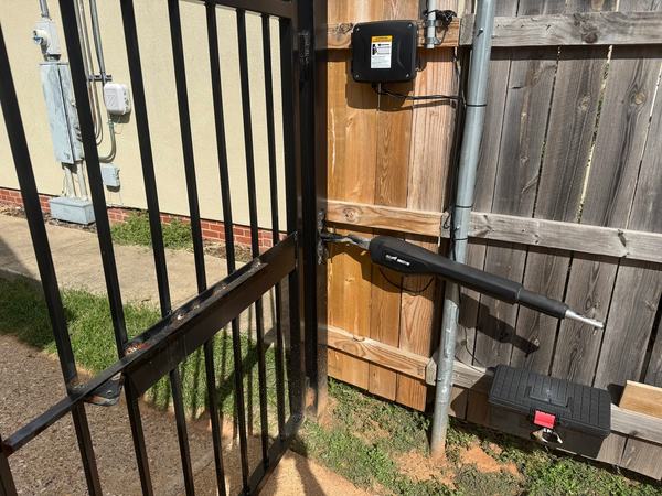 Somebody welded raw, unpainted steel onto a powder-coated gate for the operator bracket. No primer, no paint, and it's already rusting.